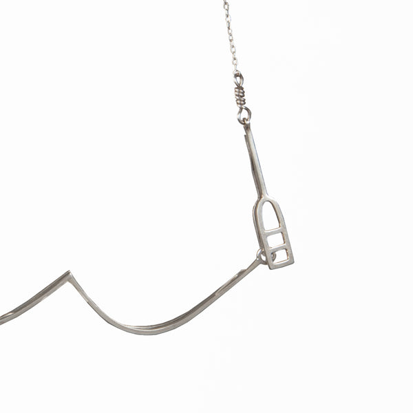 Detail of the buoy clasp on the Sailing Necklace with a moving sailboat on a wave, from a collection of fun and playful kinetic jewelry by Tinker Company.