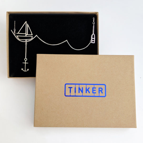 Silver Sailing Necklace with Moving Sailboat from a collection of fun and playful kinetic jewelry by Tinker Company, shown in Tinker gift box. Sustainable jewelry and recycled packaging both made in the Unites States.