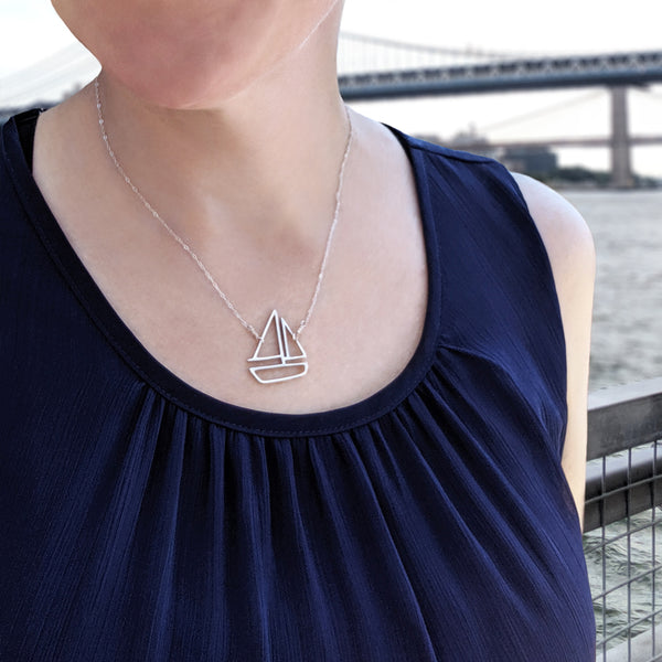 Sailboat Pendant in Sterling Silver. Shown on model in front of the Manhattan Bridge. Nautical jewelry sustainably made in New York City.