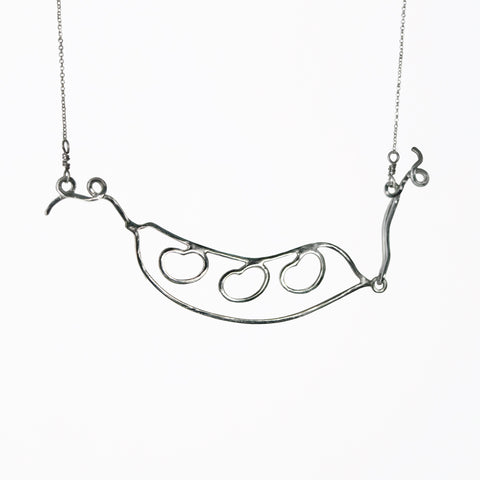 Silver Bean Pod Necklace has an outline of a peapod with three beans on the inside and curling tendrils on the ends. From a collection of fun and playful kinetic silver bean jewelry by Tinker Company.