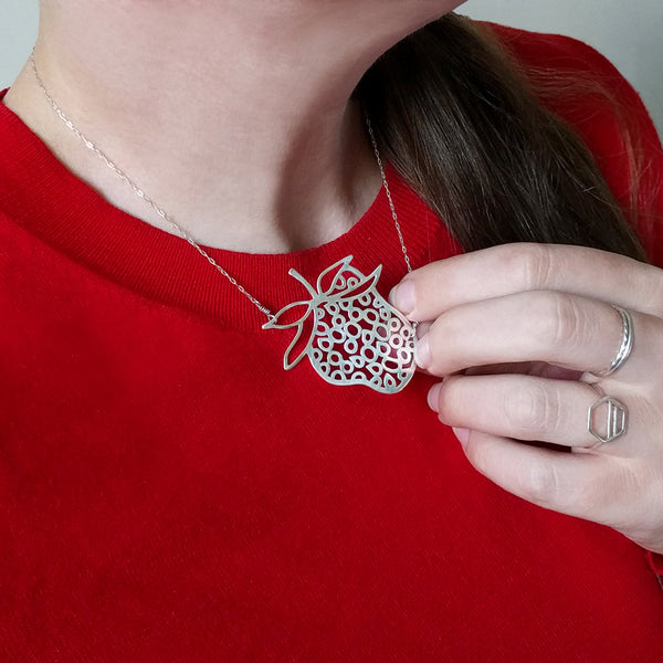 Strawberry Necklace, a fun and playful design from the Crave Collection, shown on model wearing red sweater.