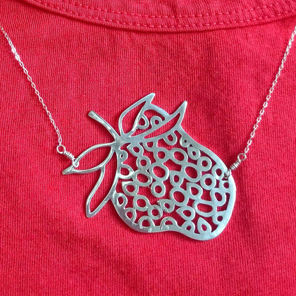 Silver Strawberry Necklace, a fun and playful design from the Crave Collection by Tinker Company. A detail of this charming necklace shown on model wearing a red shirt.