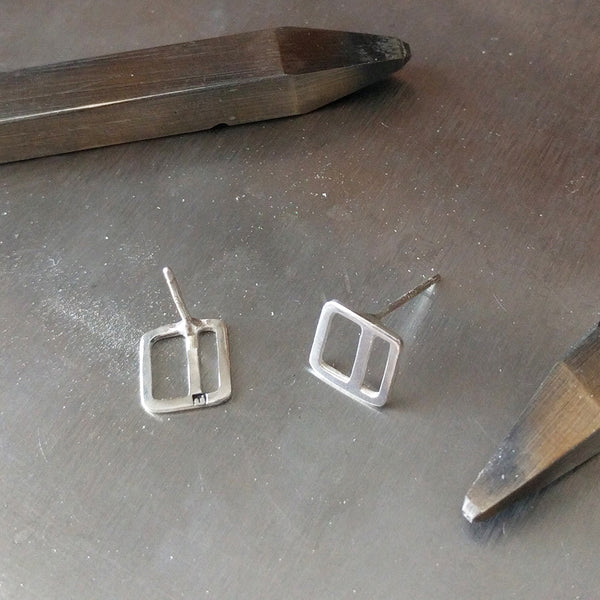 A pair of Square Stripe Stud Earrings, in progress with stamping tools, showing the detail of the Tinker maker's mark.