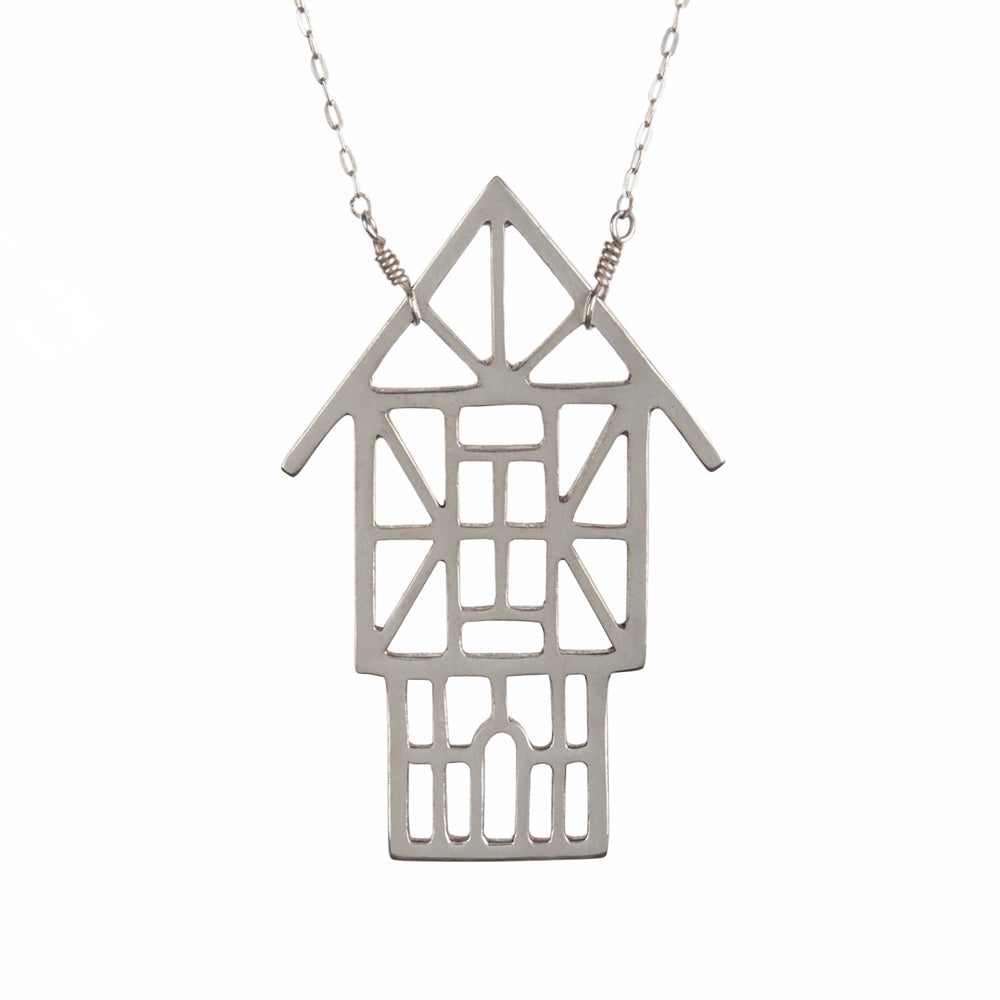 The Tudor Ski Chalet Necklace is a sterling silver outline of a Tudor style house designed and made by Tinker to capture your favorite winter vacation memories.